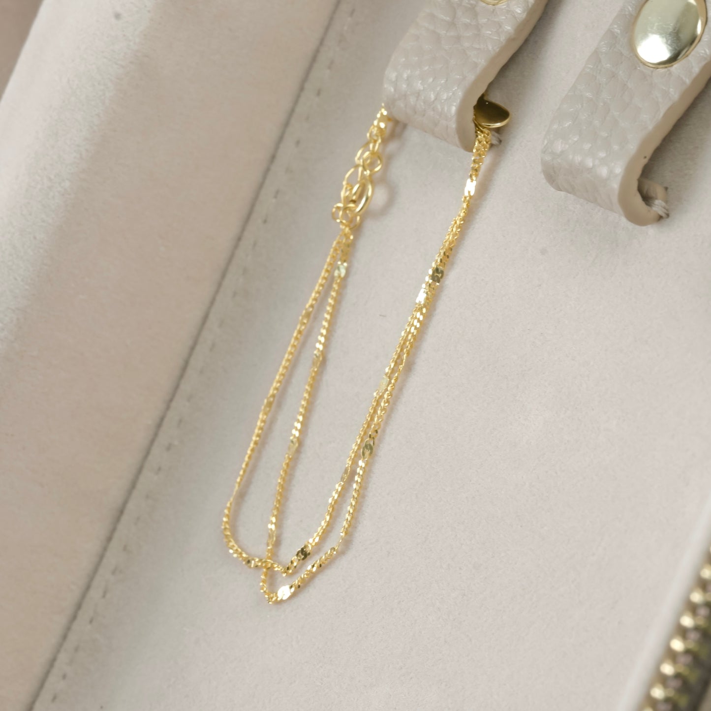 Dainty gold bracelet on a light gray surface