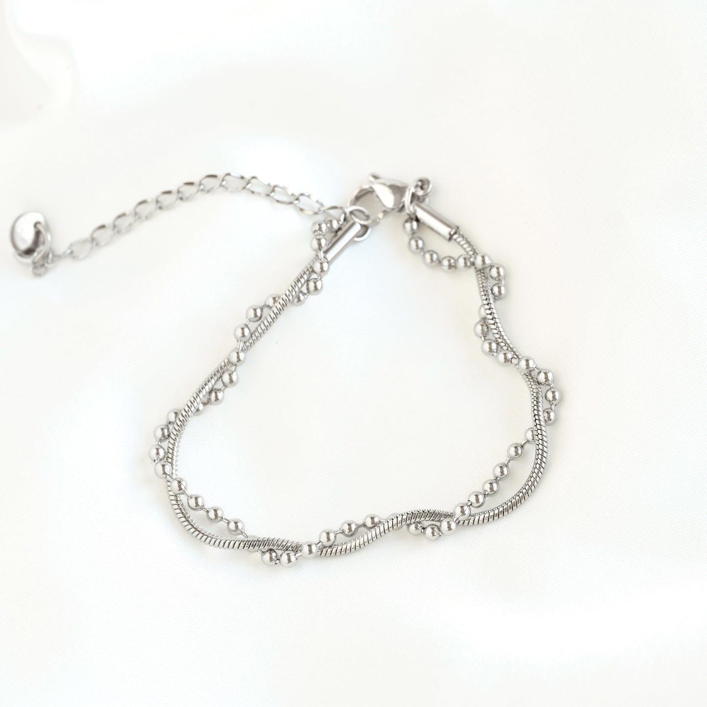 Top view of a silver-toned mixed chain bracelet with a textured snake chain  and beaded chain, displayed on a clean white background.