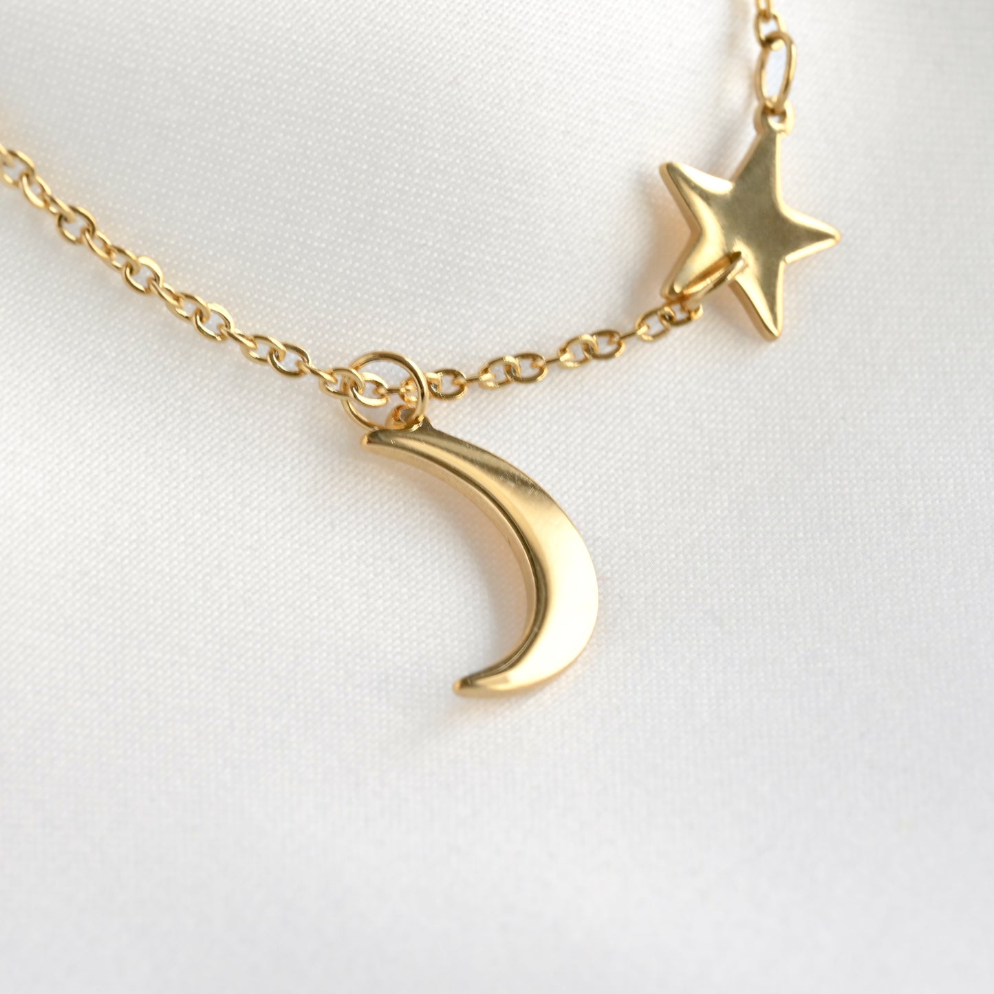 Close-up view of star and moon pendants on gold necklace on a white background