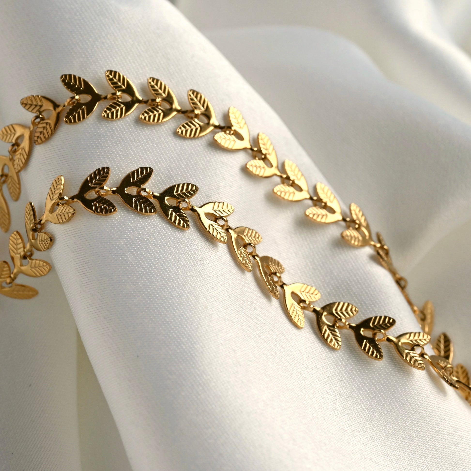 Gold flat wheat chain bracelet on a white fabric background