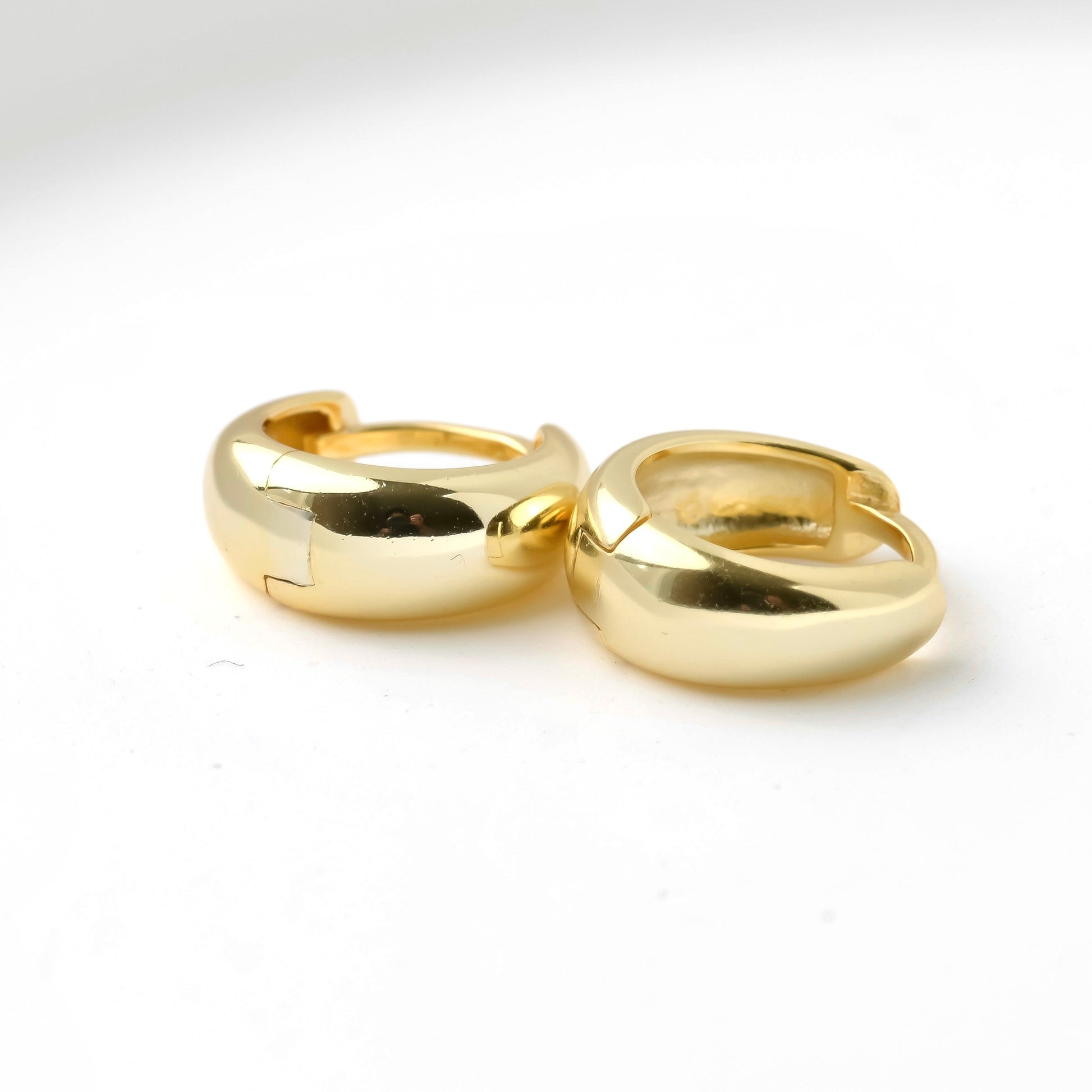 Pair of tapered gold dome hoops on a white background