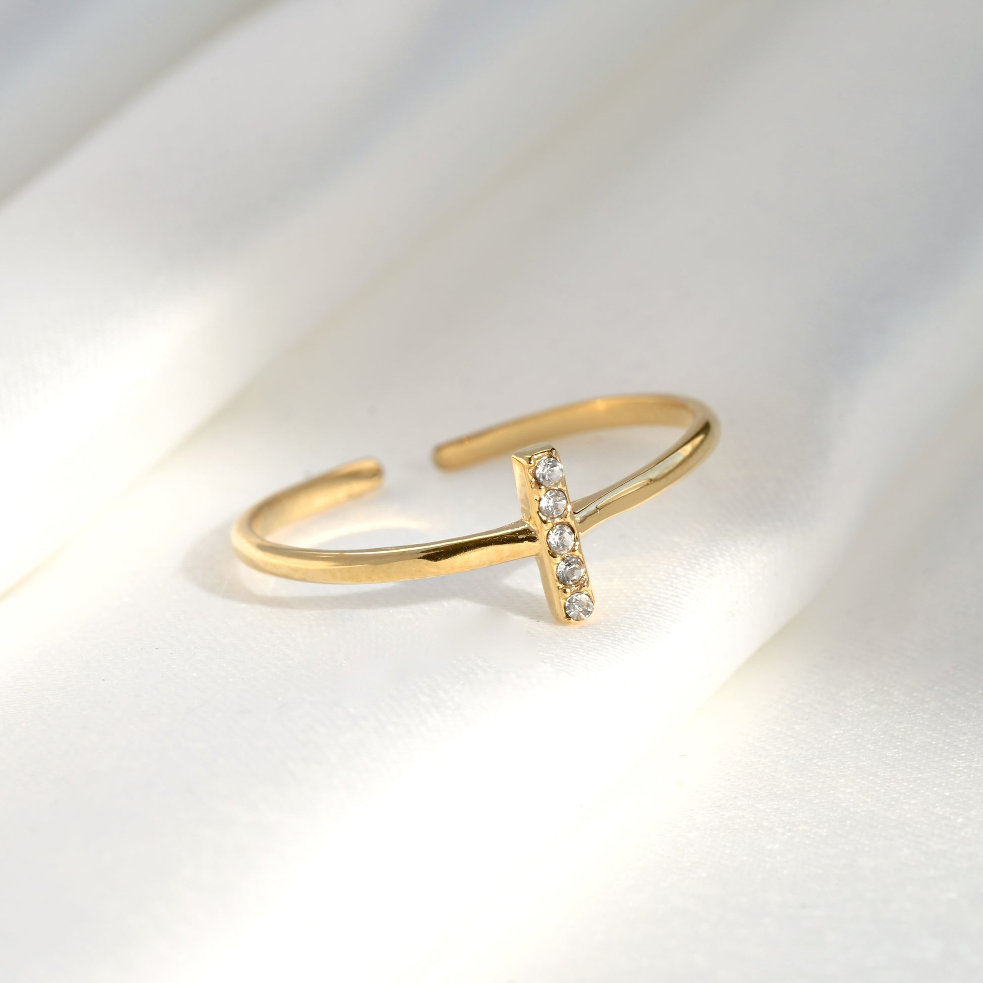 Open gold ring with a small diamond bar on a light gray background