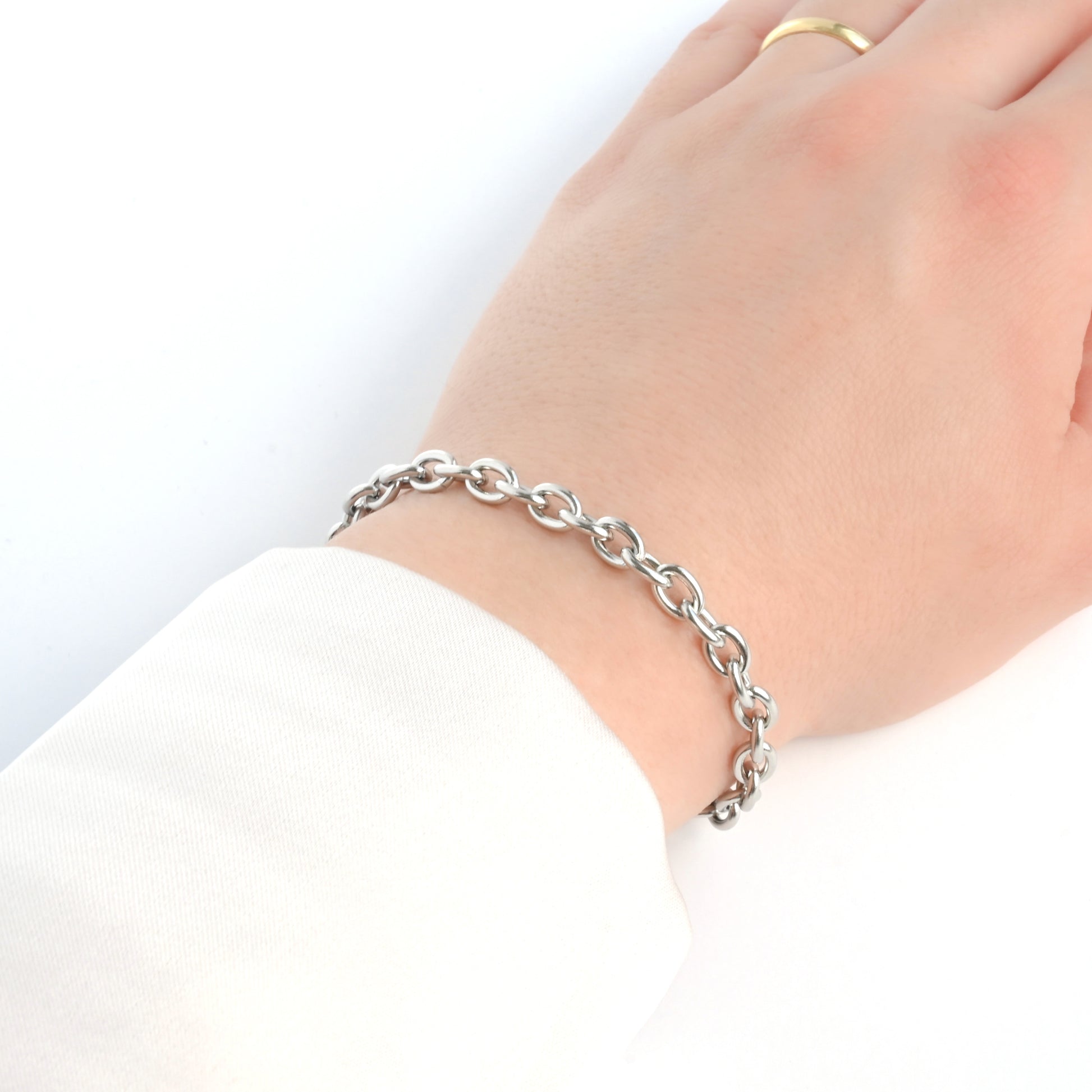 Rolo chain bracelet on a wrist with a white background