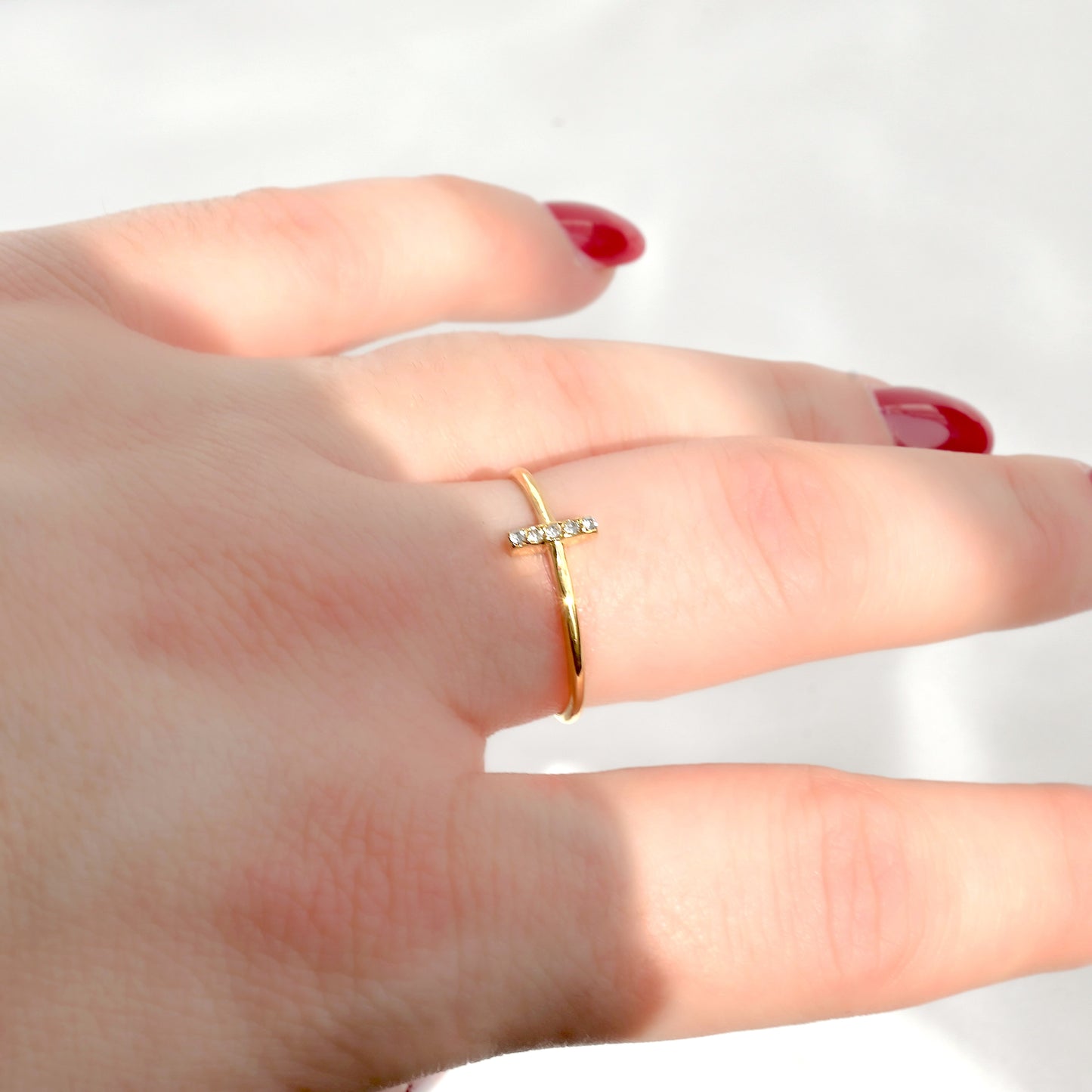 Gold ring with small diamonds on a hand against a white background stones sparkling under direct sunlight