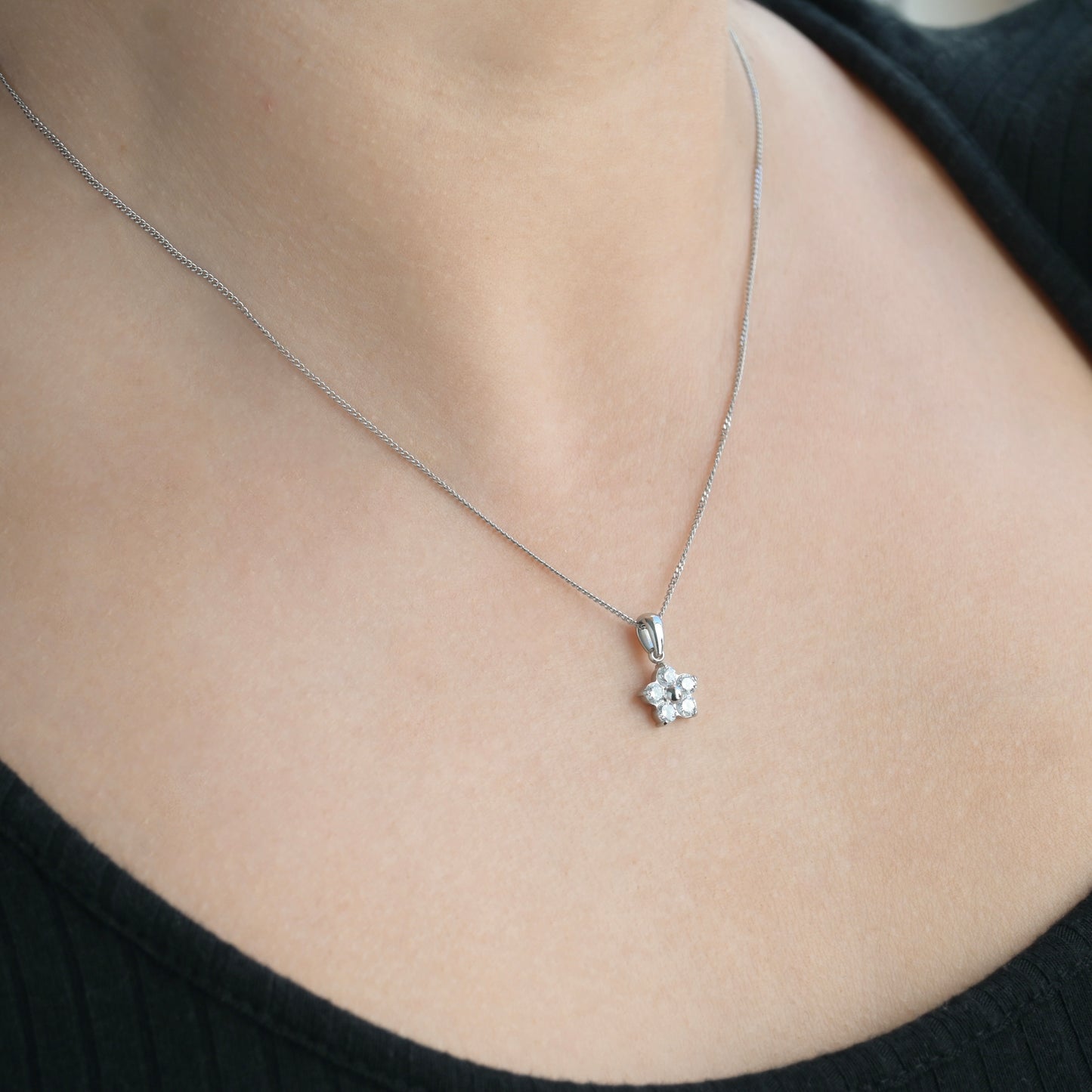 Silver flower necklace on a person wearing a black top