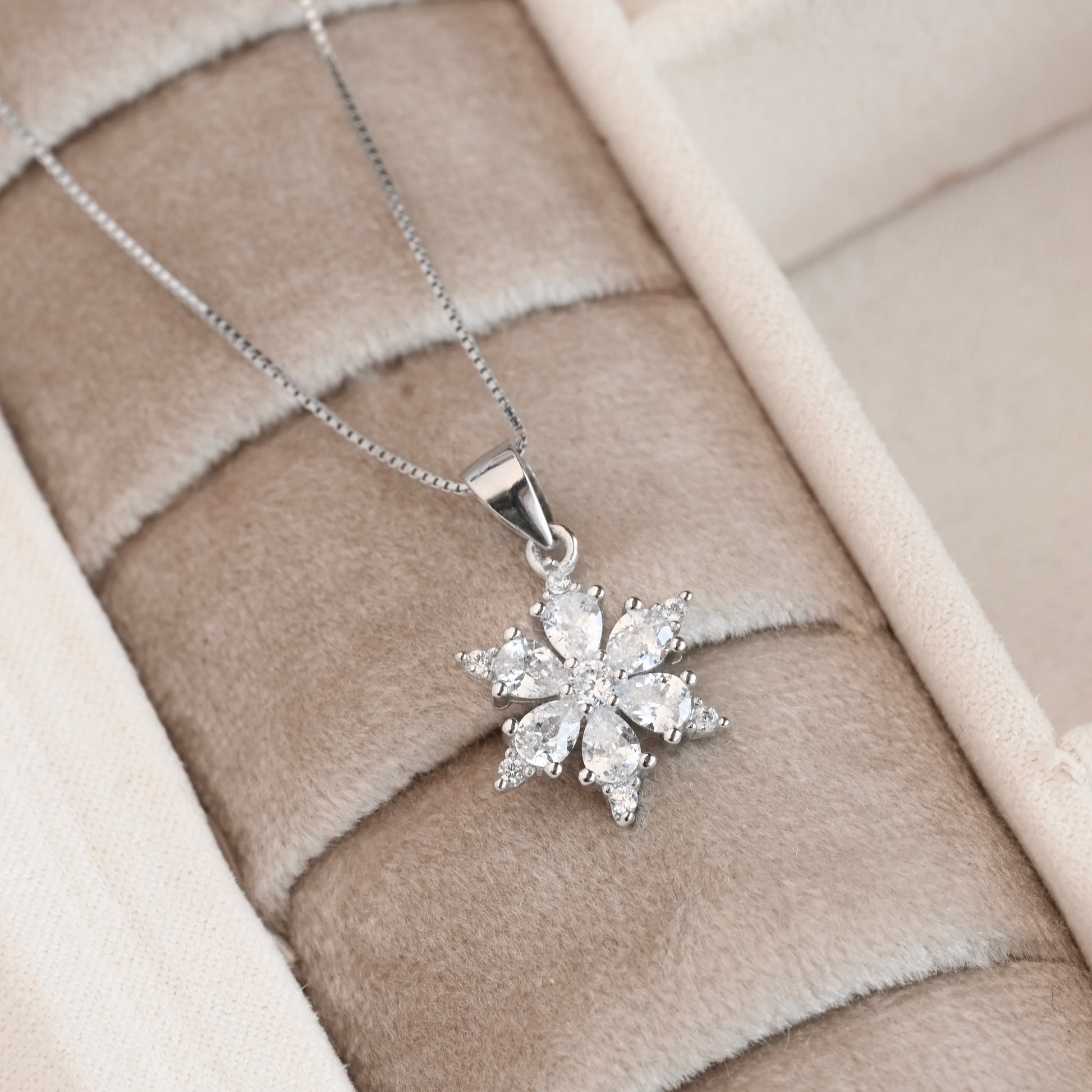 Silver snowflake pendant necklace on a soft fabric background