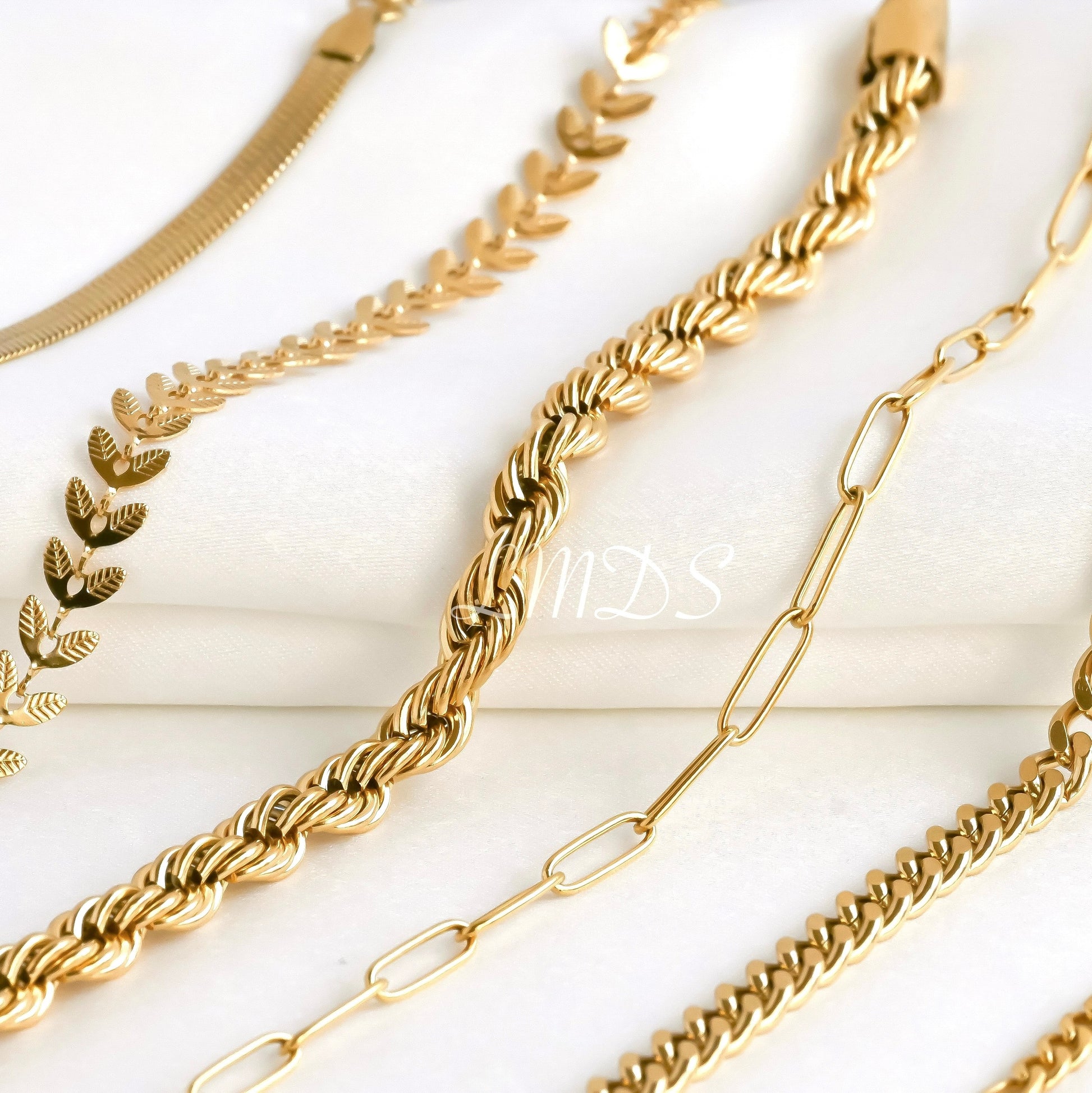 Gold chains of various designs on a white background