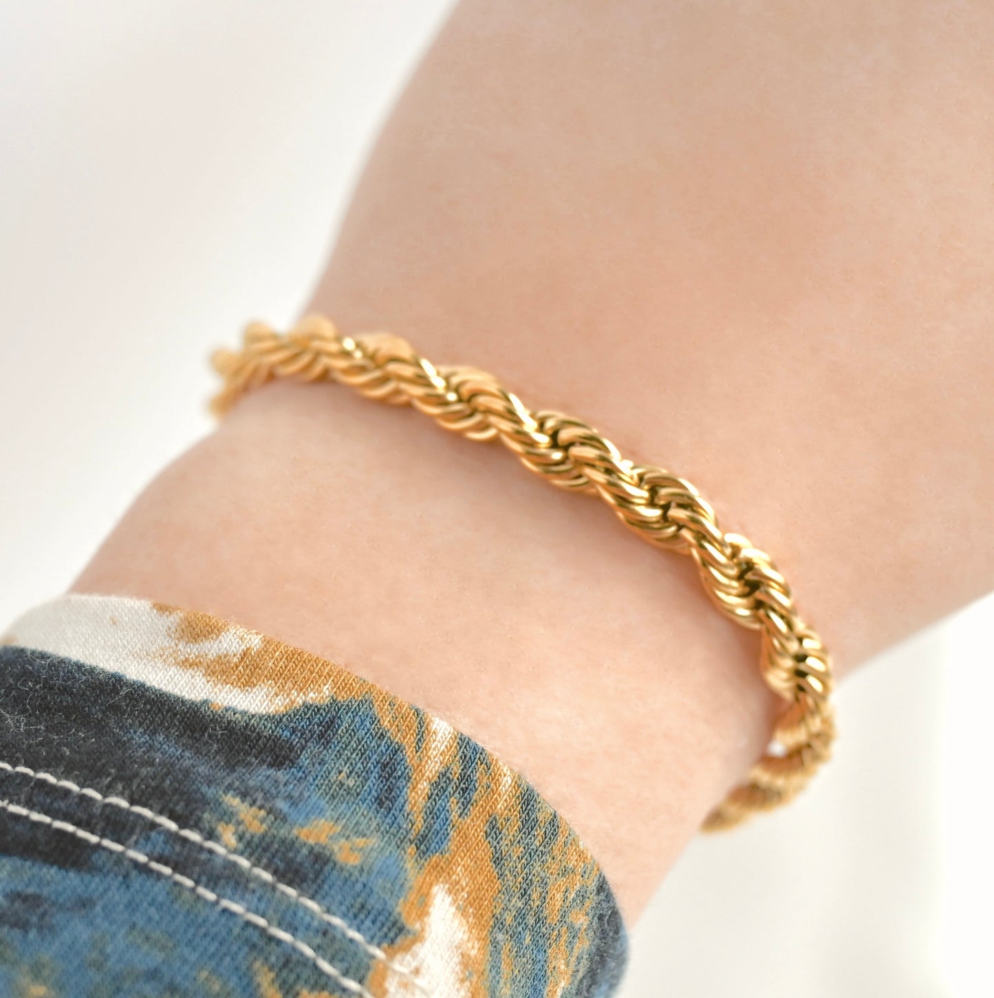 Chunky twisted rope bracelet on a wrist with a blurred background