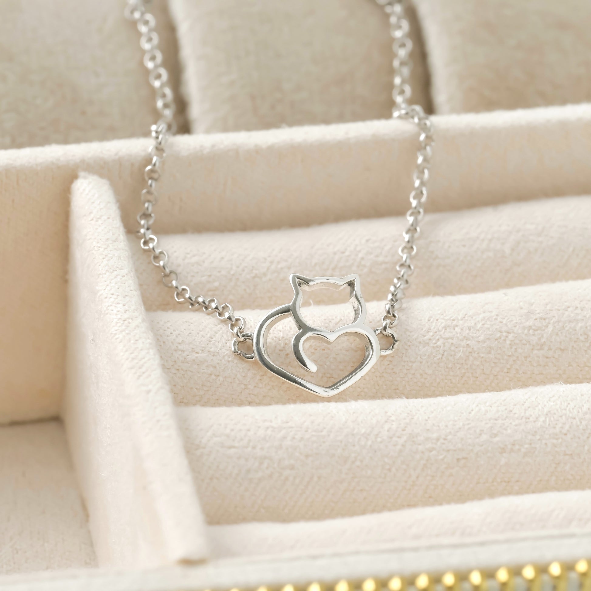 Silver cat bracelet on a beige jewelry display.