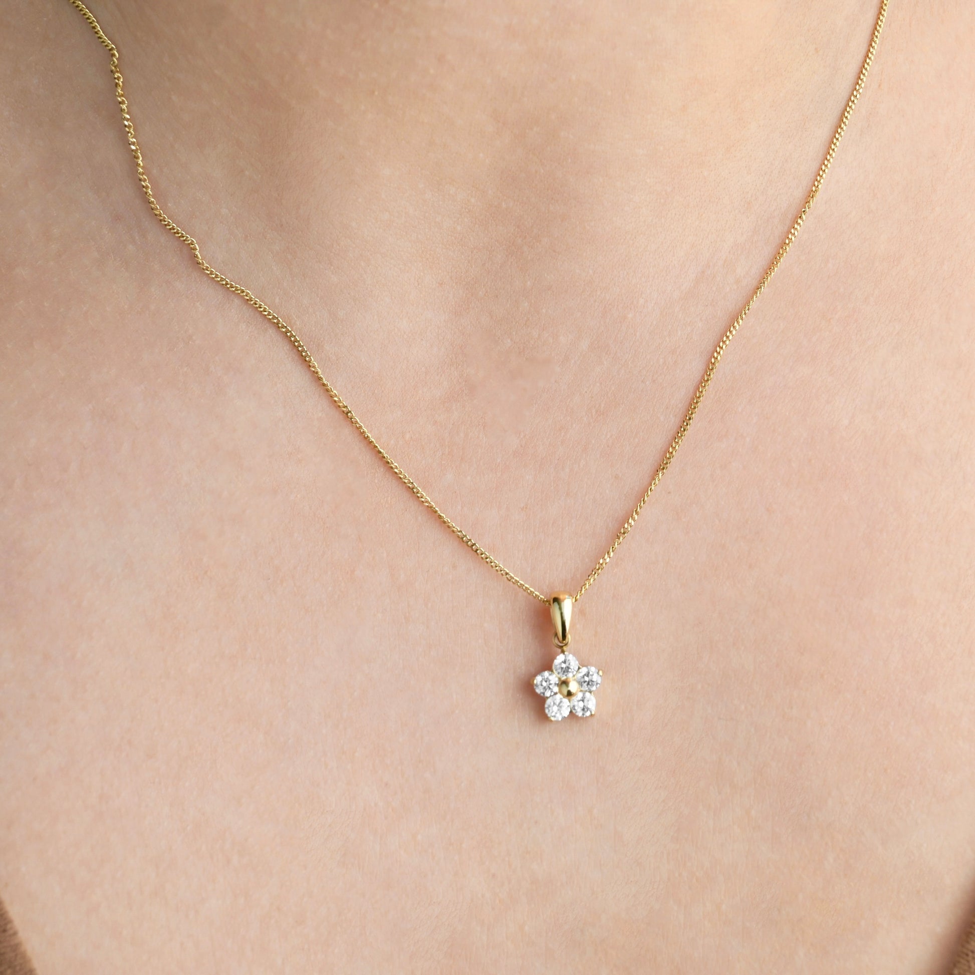 Gold necklace with a small diamond pendant on a person's neck