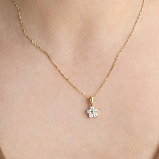 Gold necklace with a small diamond pendant on a person's neck