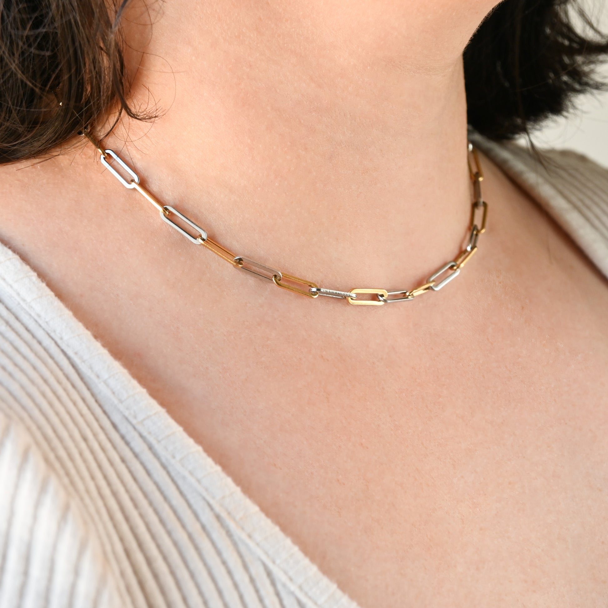 Mixed metal paperclip link necklace on a person wearing a white top