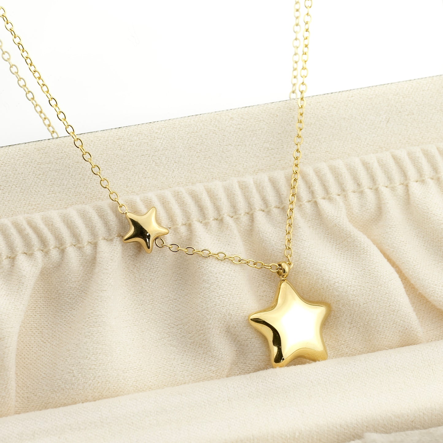 Gold chubby star necklace on a beige fabric background