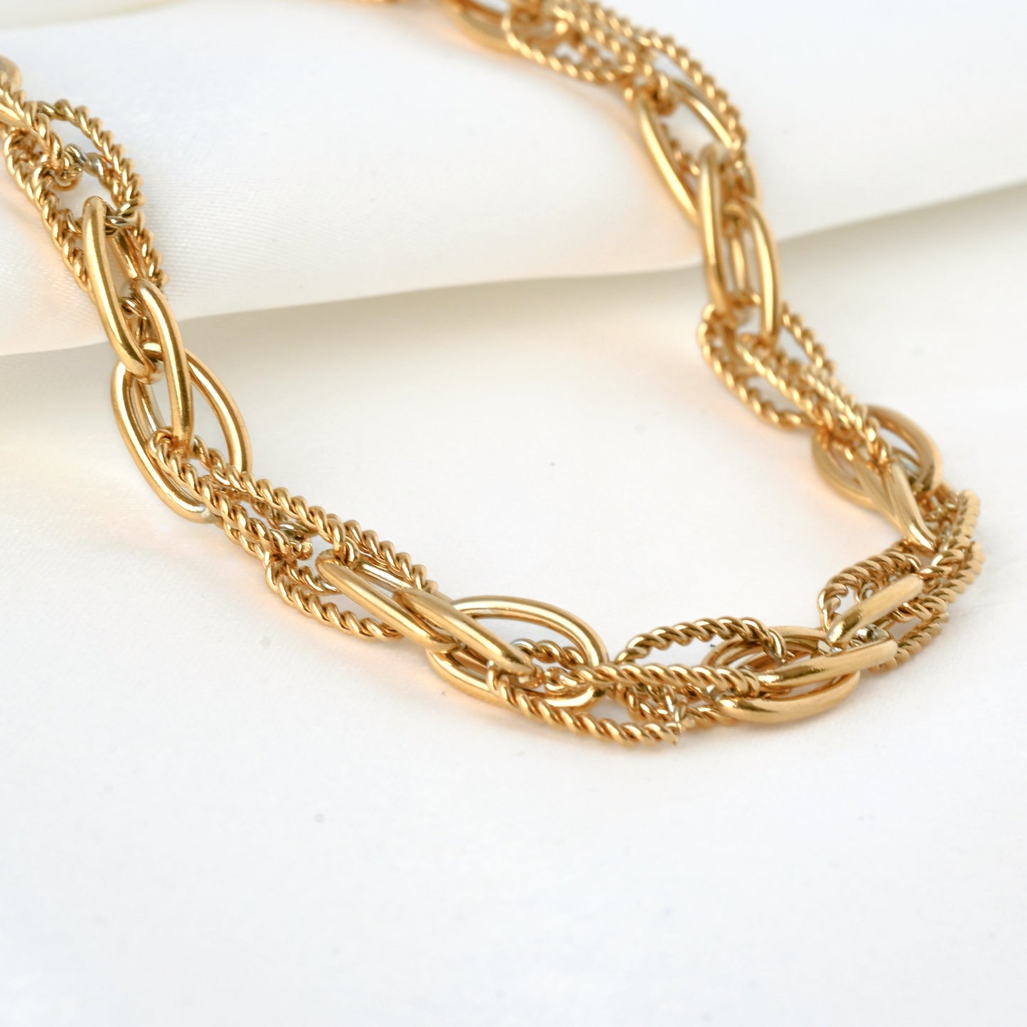 Gold mixed link chain necklace on a white background