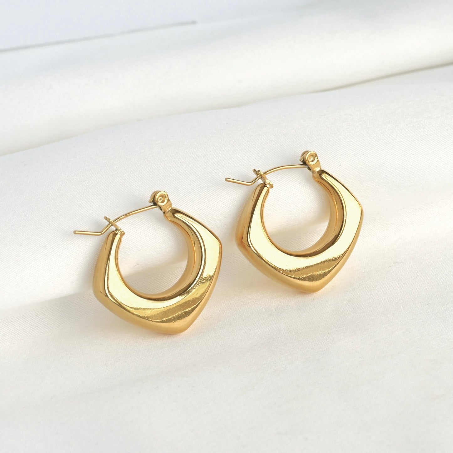 Gold geometric hoop earrings on a white background