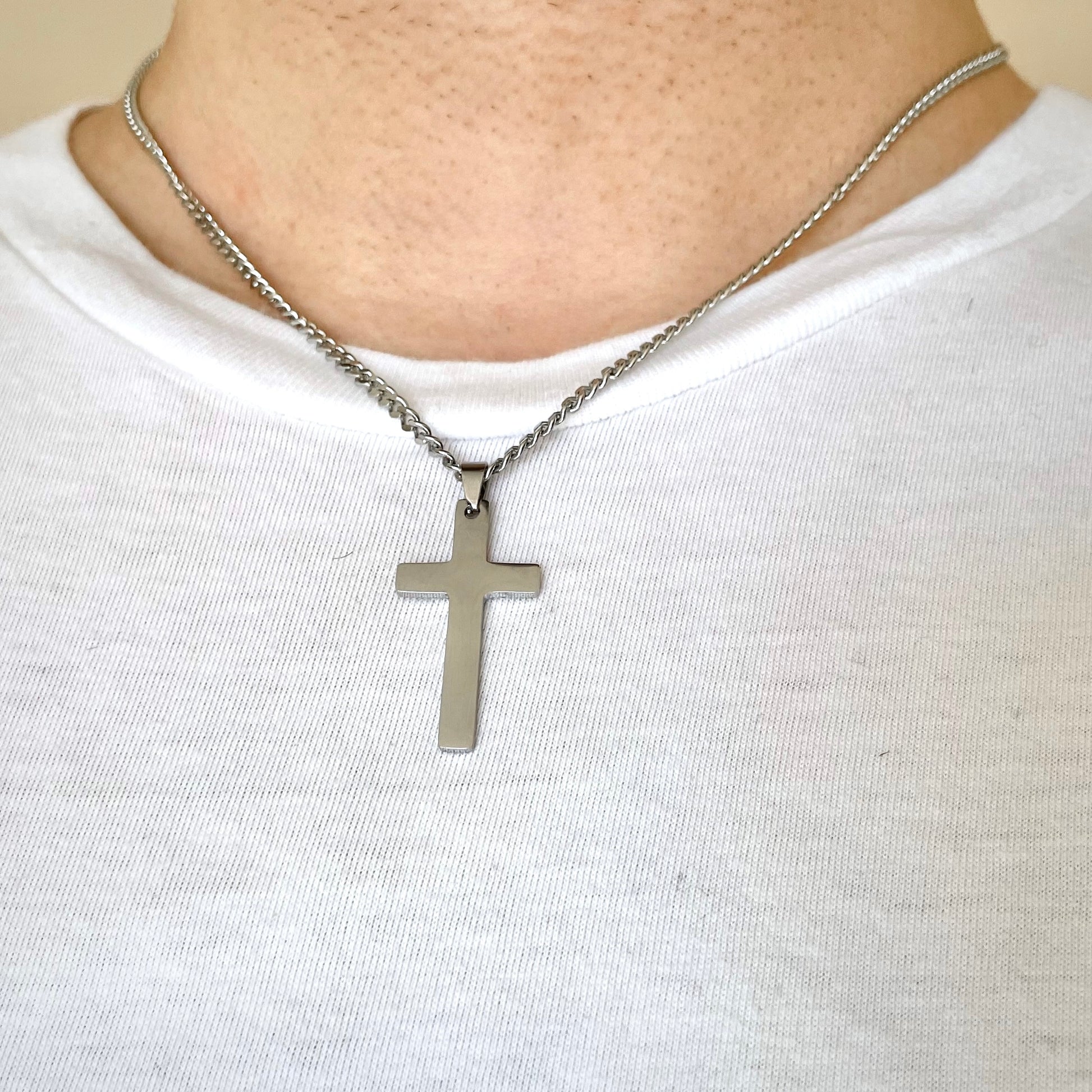 Silver cross necklace on a man wearing a white shirt