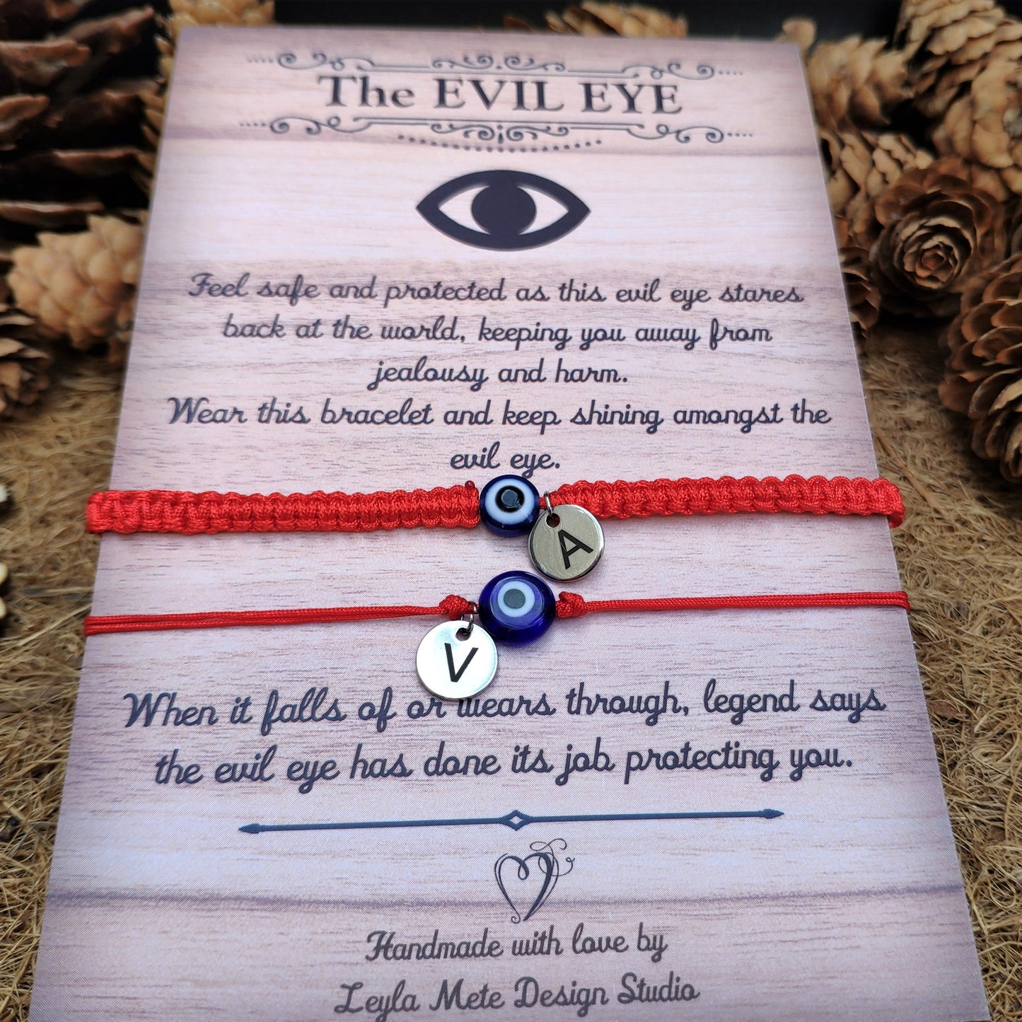 Two red bracelets with evil eye designs on a decorative card with text.
