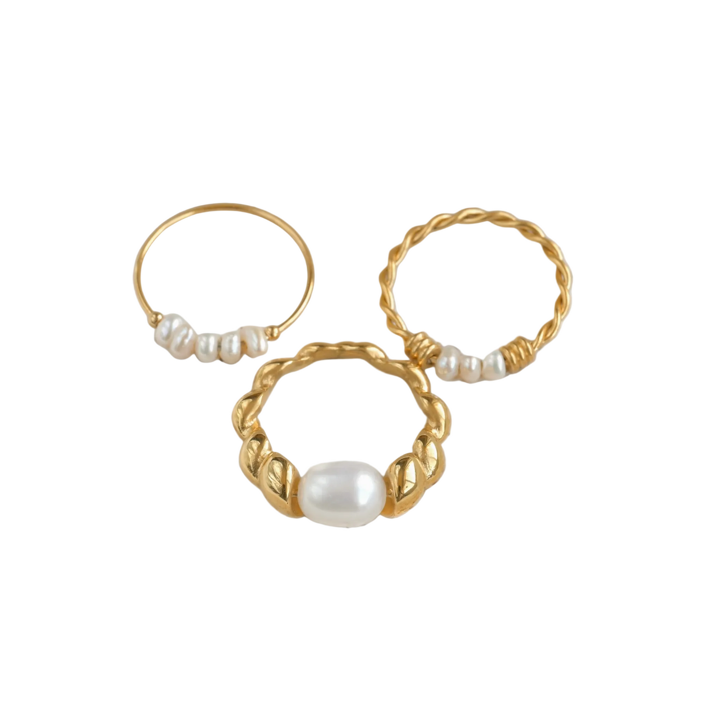 Top view of minimalist gold rings with pearl accents on a white surface