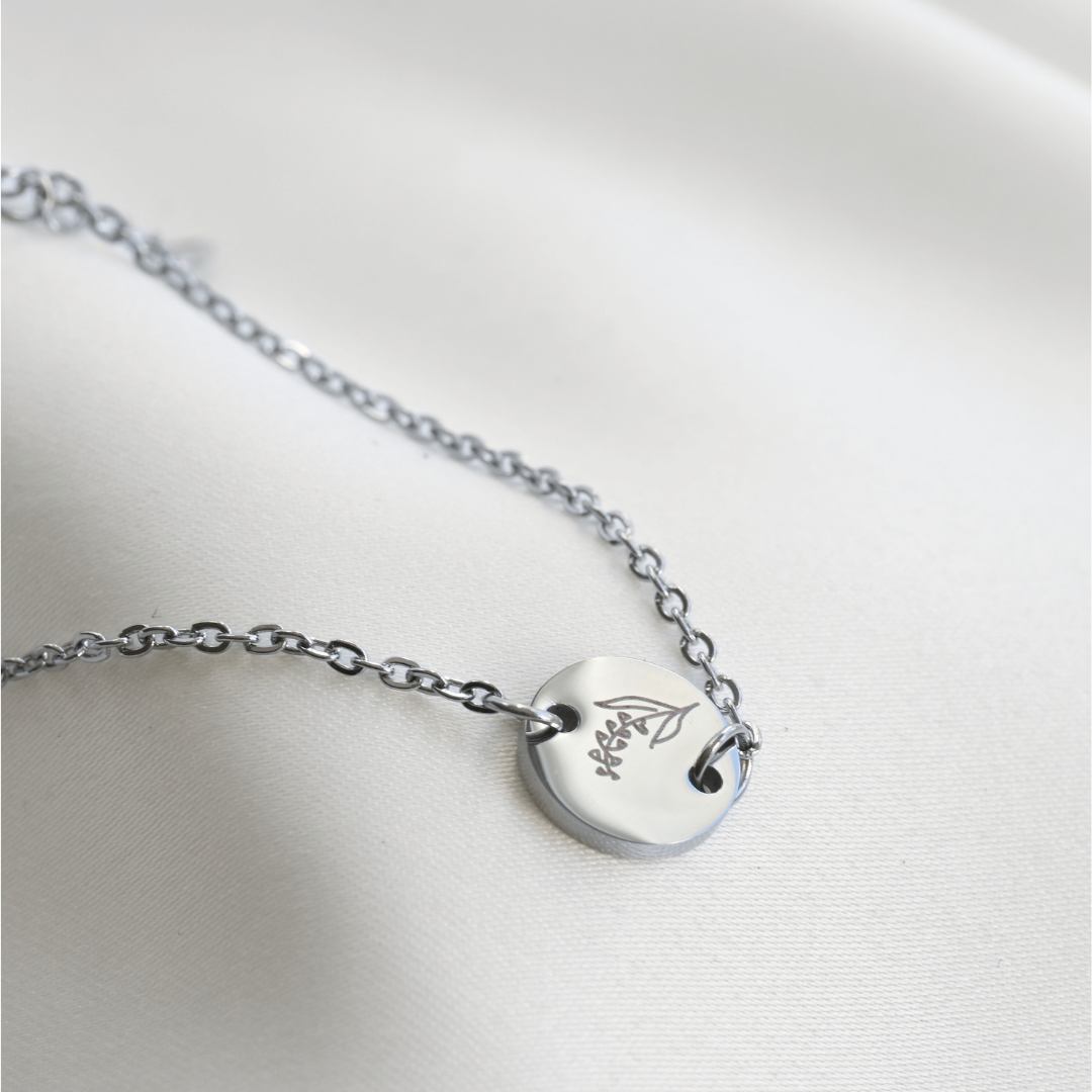 Silver december birth flower bracelet with a coin charm  on a white background