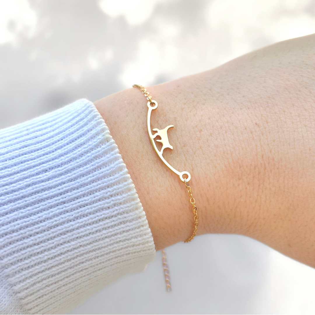 Gold walking kitten bracelet on a wrist with a blurred light background