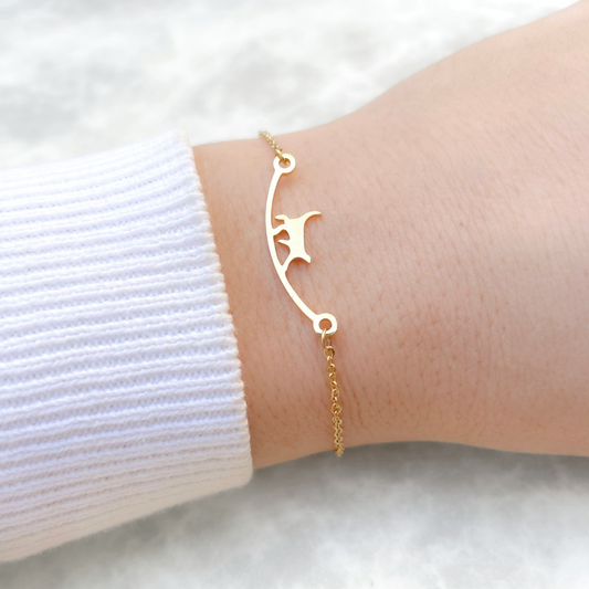 Gold cat bracelet on a wrist against a white background