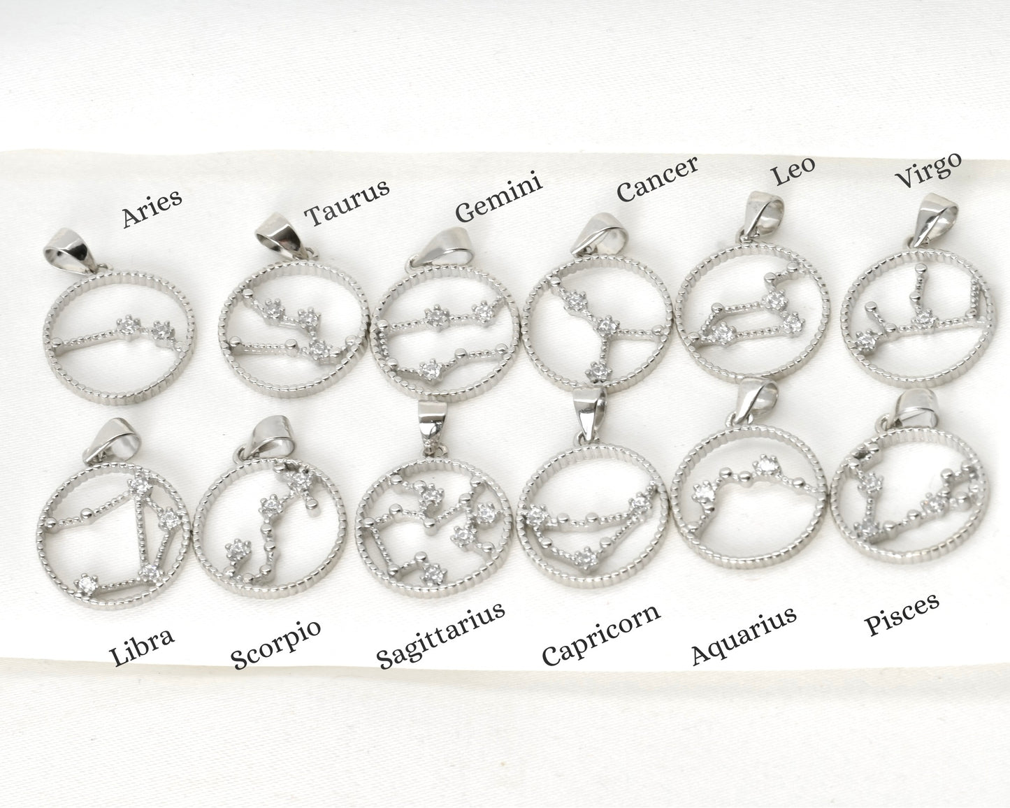Set of  CZ zodiac sign pendants with star constellations on a white background with labels