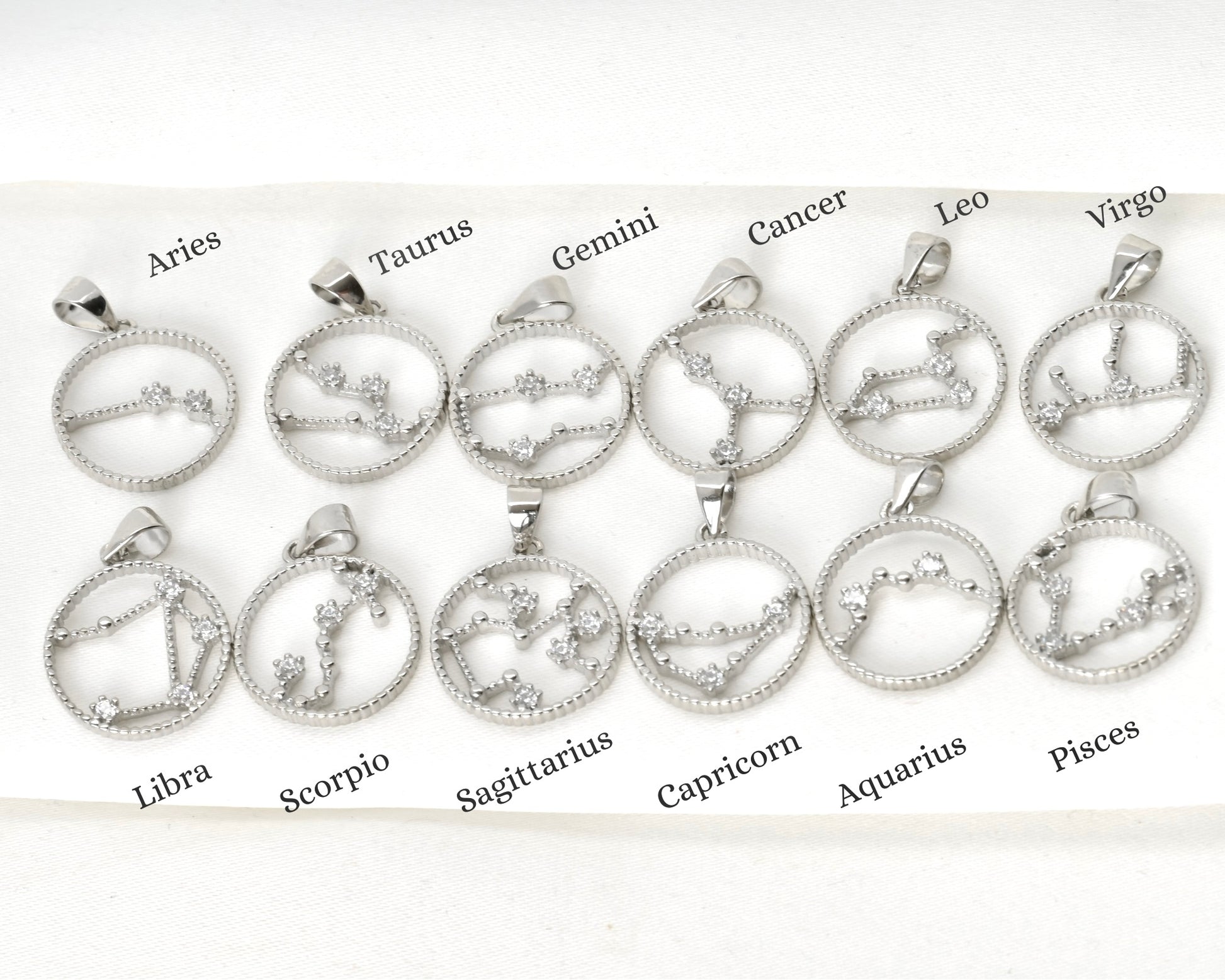 Set of  CZ zodiac sign pendants with star constellations on a white background with labels