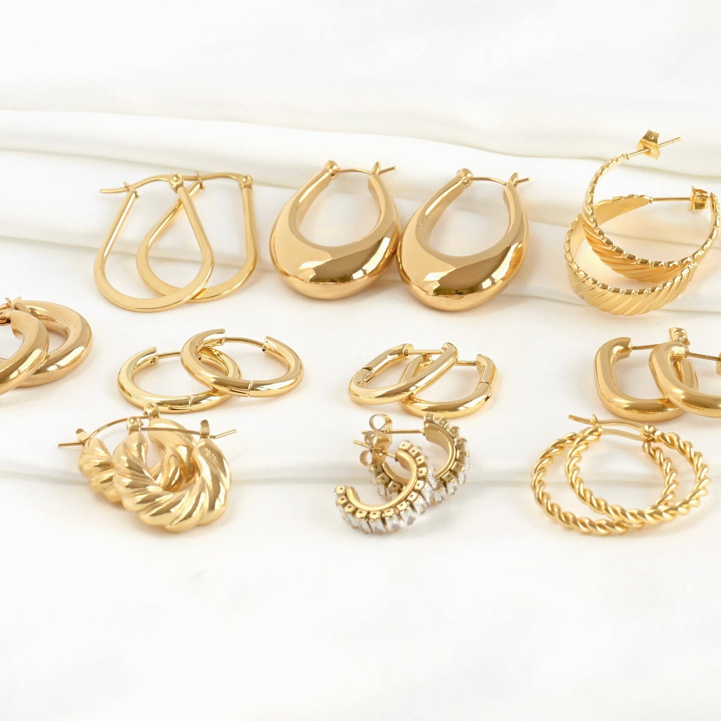 Front view: Collection of gold hoop earrings on a white background