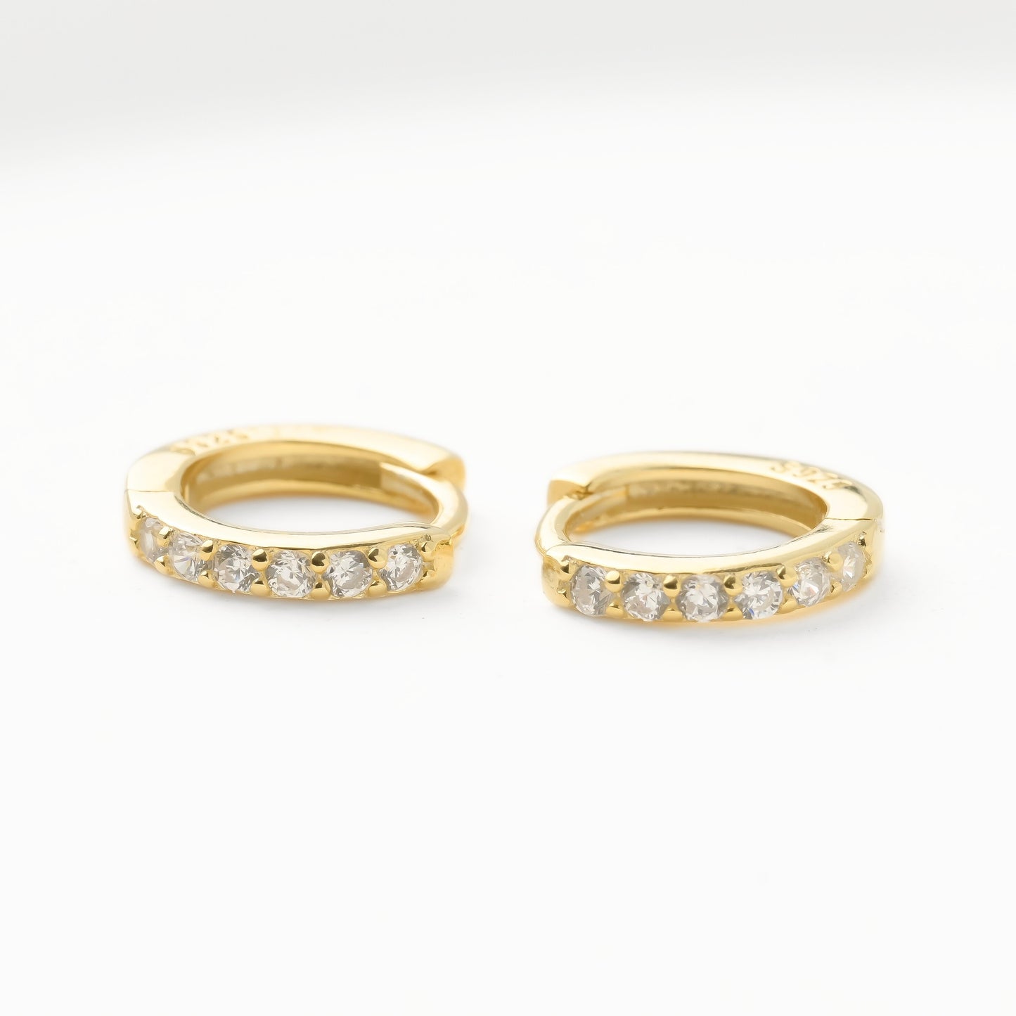 Gold pave CZ hoop earrings with embedded diamonds on a white background