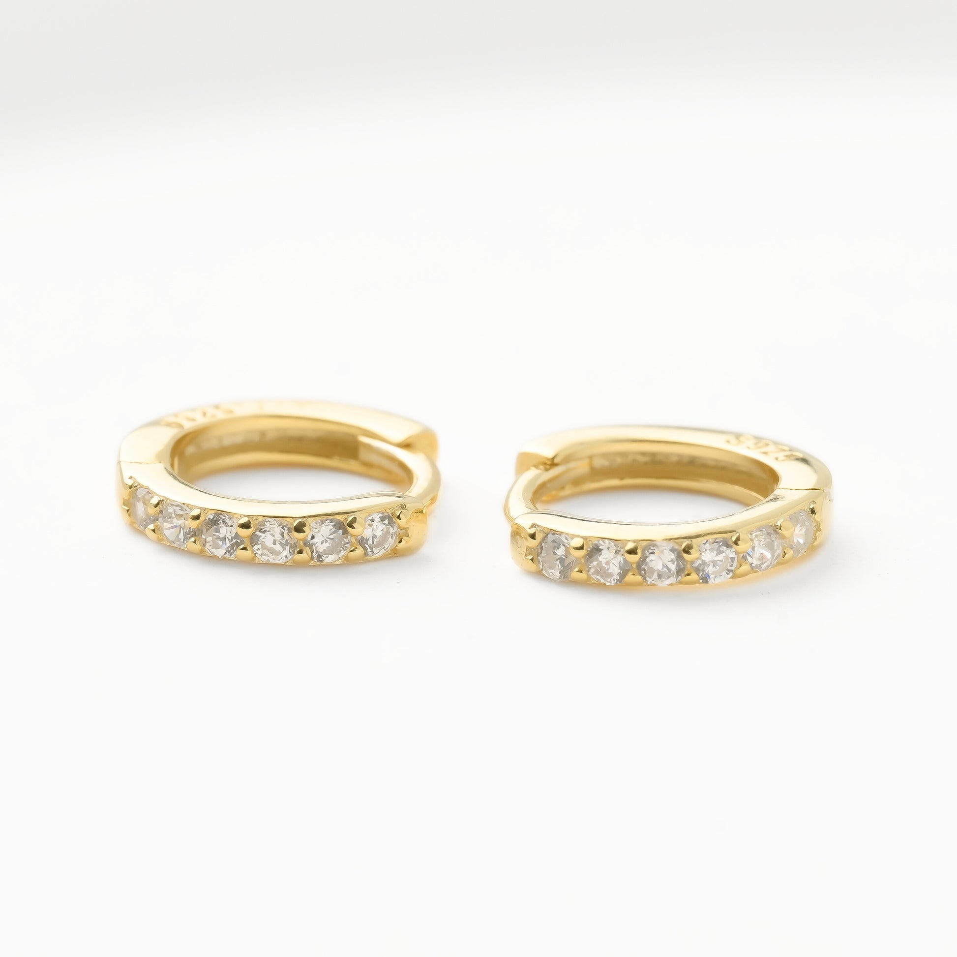 Gold pave CZ hoop earrings with embedded diamonds on a white background