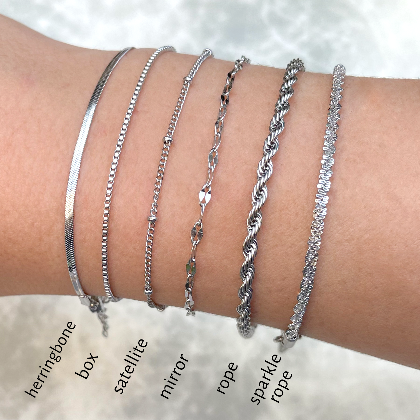 Collection of silver bracelets on a wrist with labels indicating each design.