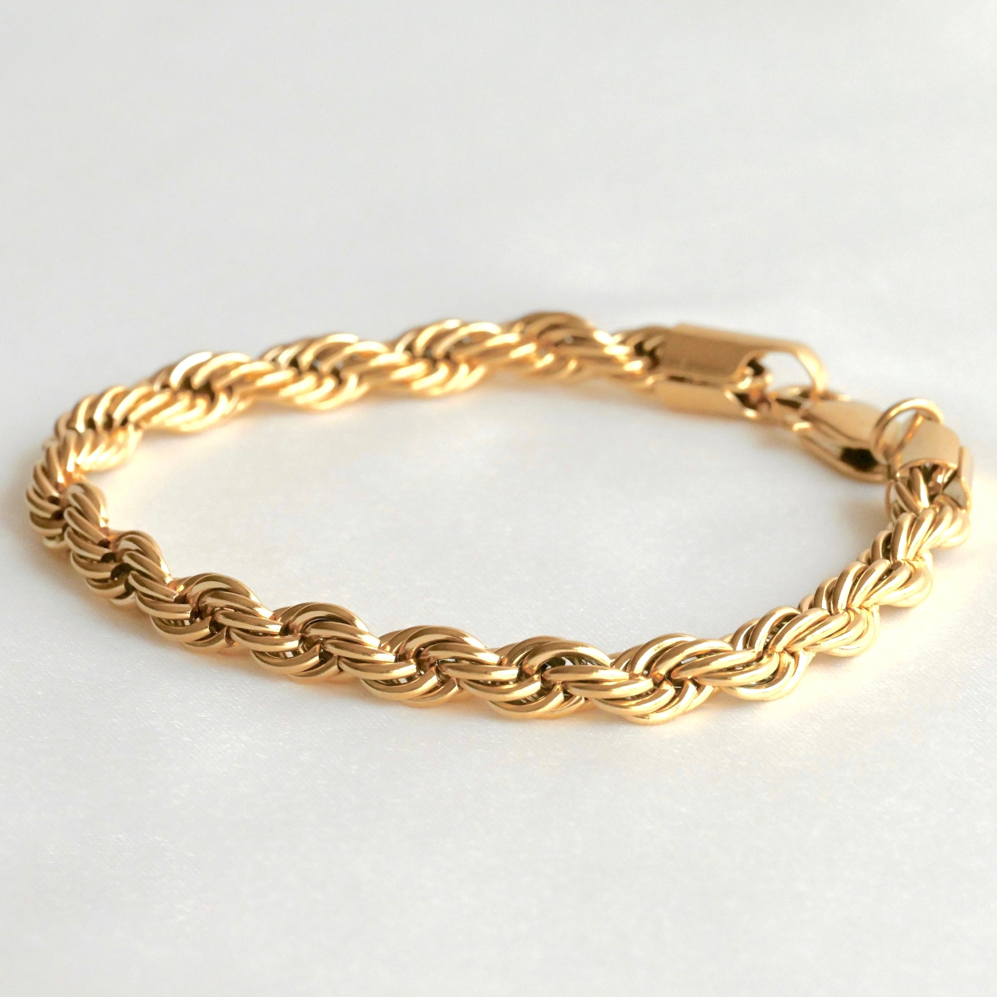 Gold rope bracelet on a light gray background