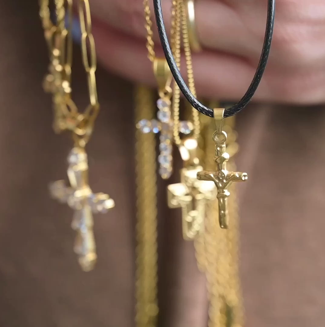 Textured vintage style cross pendants on various chain styles in hand, the stones sparkling and metal shining as they catch light, while the person moves her hand.
