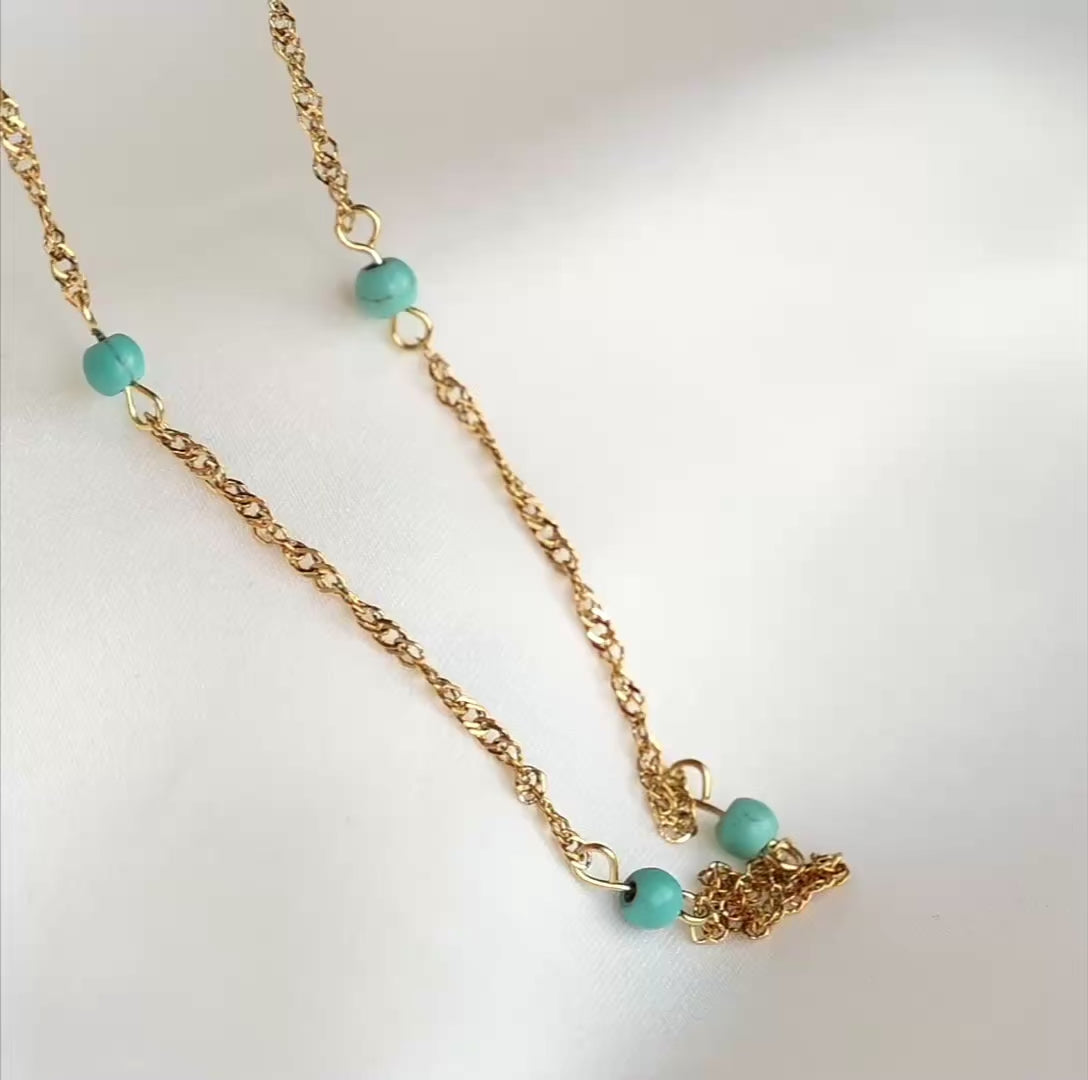 Gold singapore chain necklace with links reflecting light as the chain moves