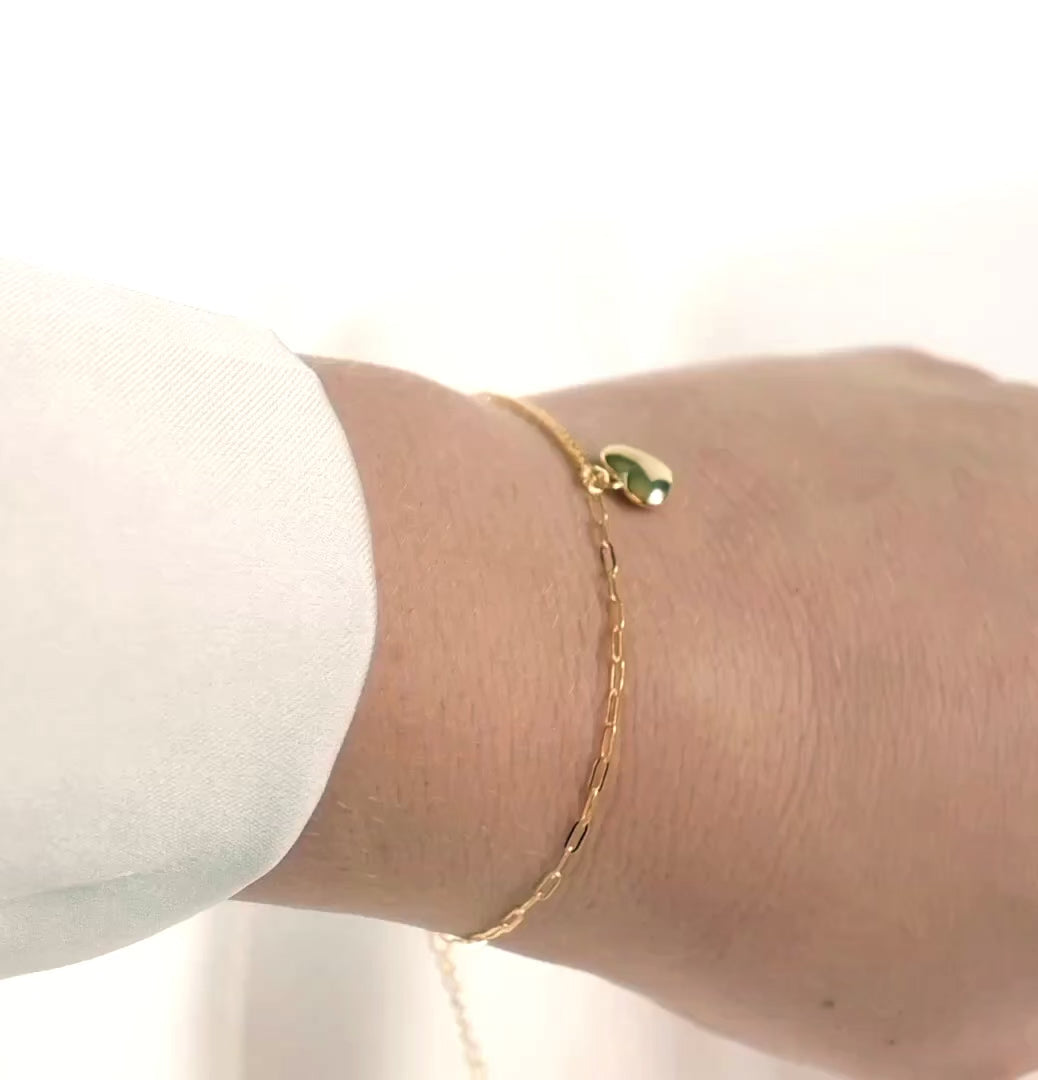 gold heart bracelet on a wrist reflecting light as the model turns her wrist