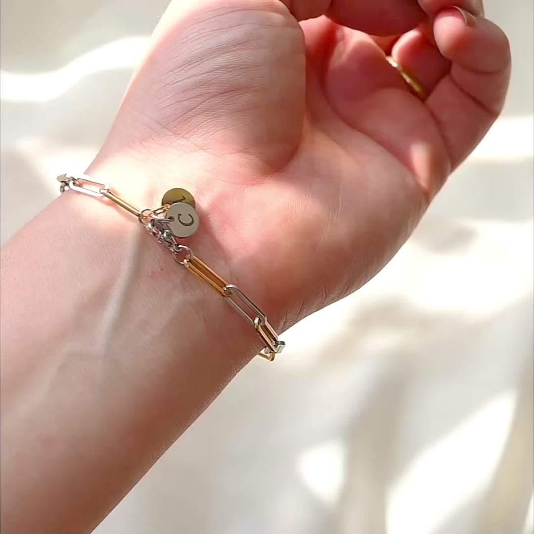 two tone thick bracelet with gold A and silver C letter charms at the clasp on a person's wrist