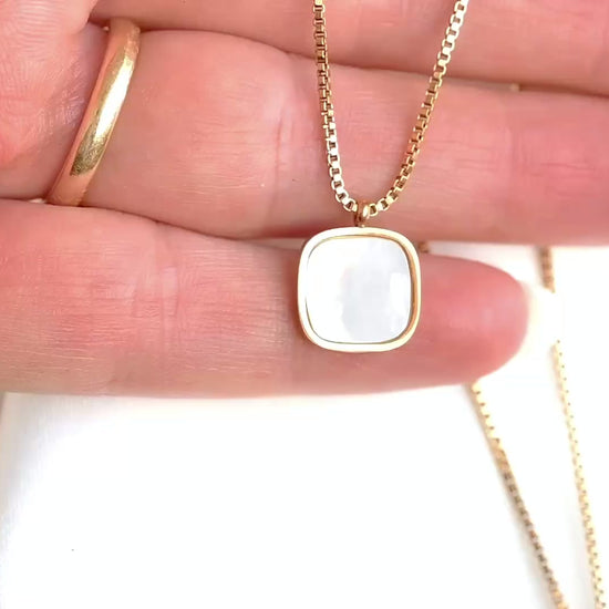 Gold box chain with a rounded square pendant with shell inlay in a person's  hand moving and showing the necklace from diferent angles