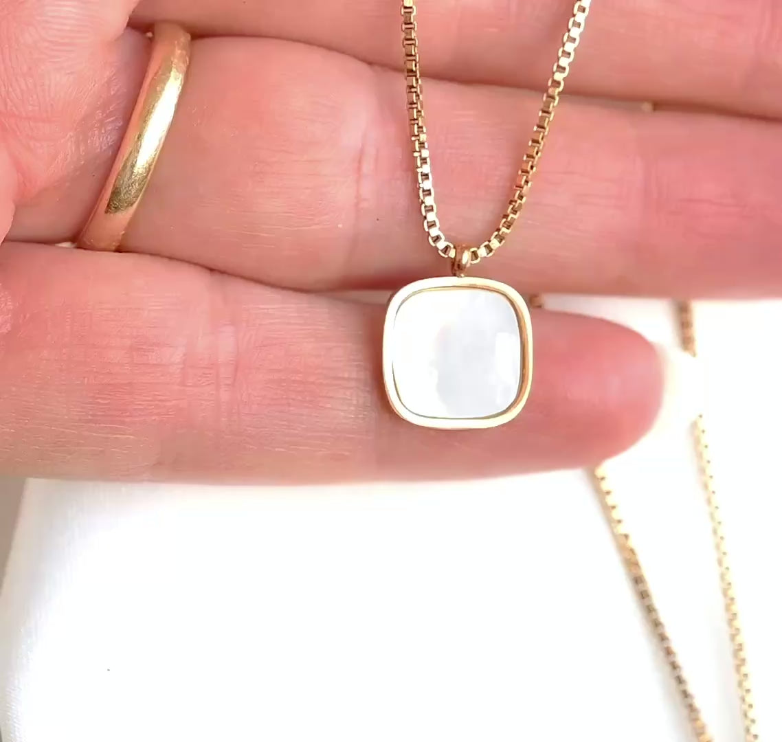 Gold box chain with a rounded square pendant with shell inlay in a person's  hand moving and showing the necklace from diferent angles