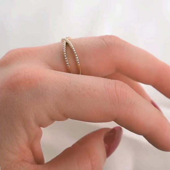 The view of dainty criss cross beaded ring from different angles on a person's finger as the hand moves