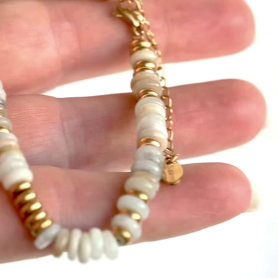 Gold bracelet with light earthy colored stones, gold spacer beads and gold clasp shown in hand from different angles.