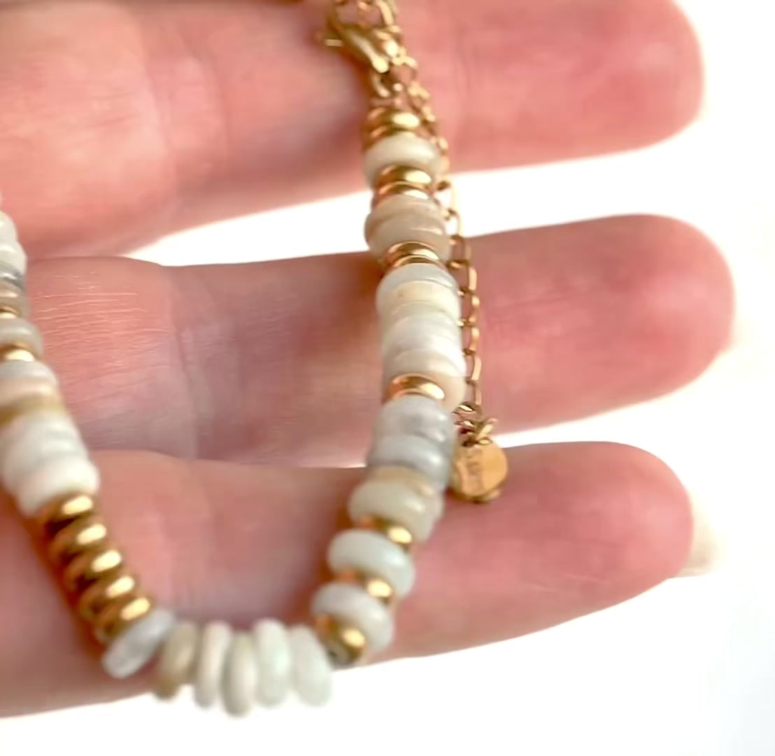 Gold bracelet with light earthy colored stones, gold spacer beads and gold clasp shown in hand from different angles.