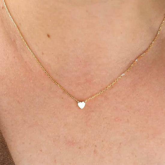 Sterling silver gold heart necklace with the chain shimmering as model turns