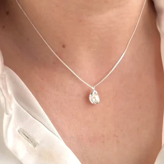 woman wearing a rhodium-plated silver oyster shell pendant, showing the necklace from different angles