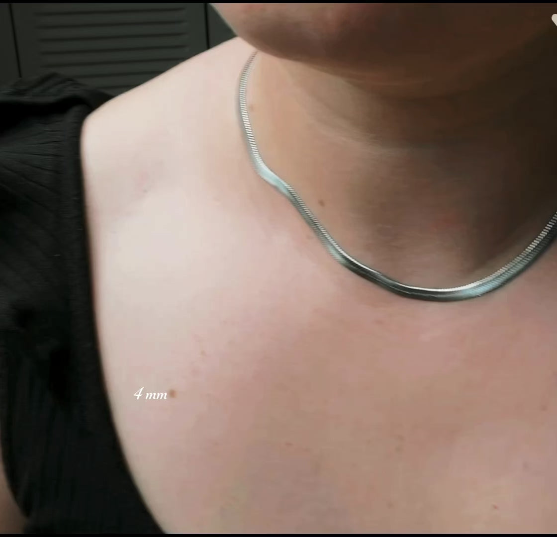 4mm silver herringbone necklace in 16 inches on a woman wearing a black blouse, the necklace catching and reflecting light as the model moves.