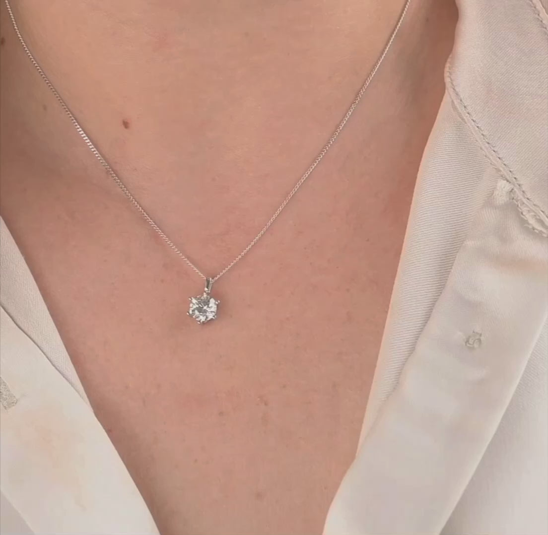 woman with a white satin shirt showing the solitaire pendant on a curb chain from different angles.