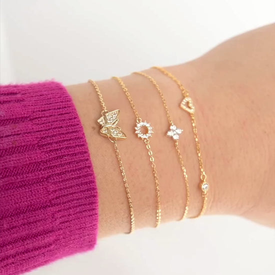 Stack of gold CZ charm bracelets with stones sparkling and chain shimmering as the hand moves