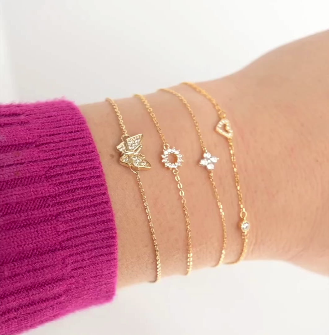 Stack of gold CZ charm bracelets with stones sparkling and chain shimmering as the hand moves