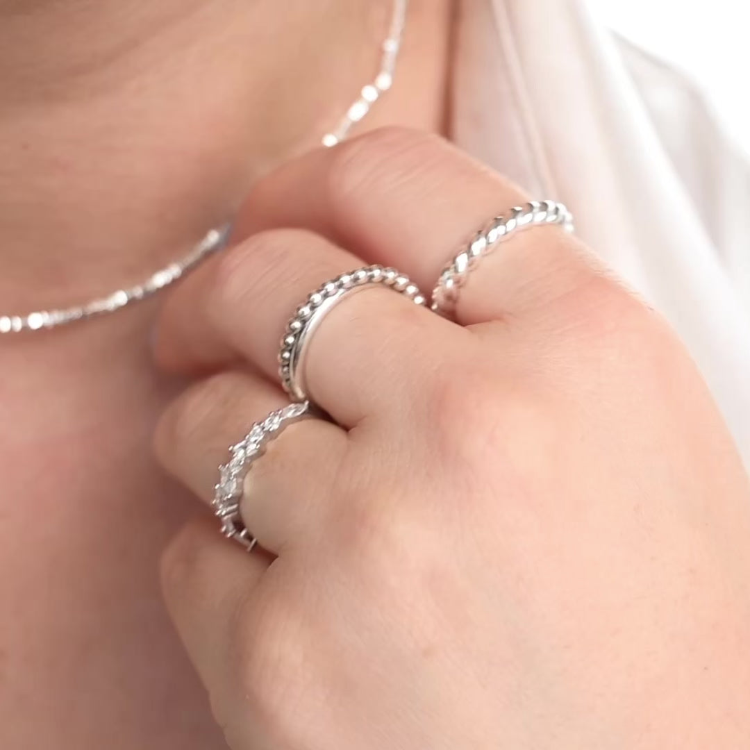 Female model wearing three silver rings on three fingers and moving her hand to show the ring from different angles