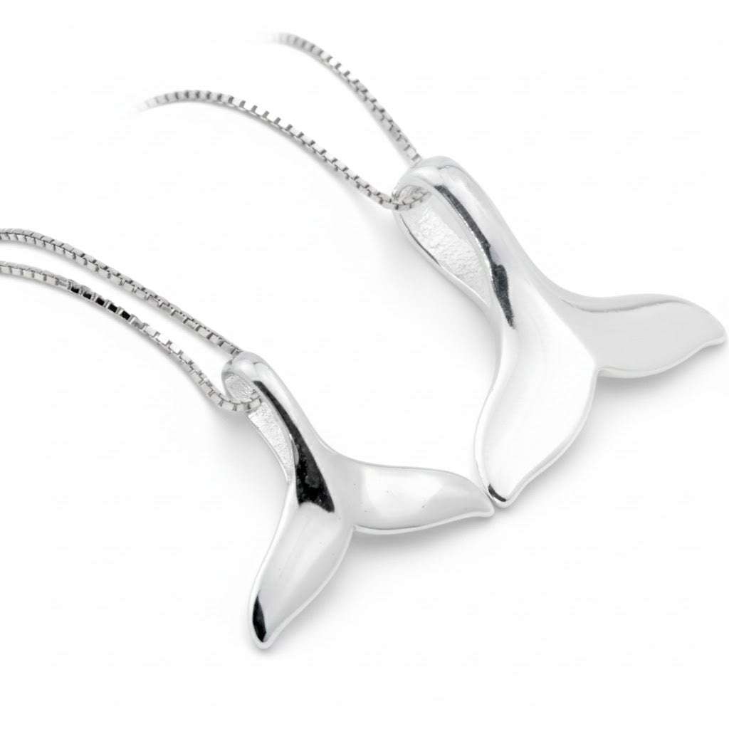 Silver whale tail pendant s, one big and one small, on a white background