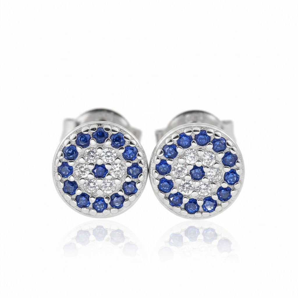 Pair of small silver eye earrings with blue and clear stones on a white background